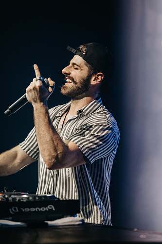 human man in gray and black shirt holding microphone person